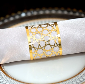 Detail of gold metal napkin ring with star pattern on a luxury white plate