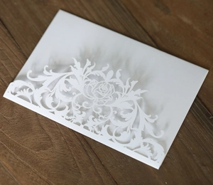 Detail of laser-cut rose patterns on white pearlescent paper wedding invitation