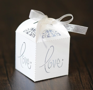 Macro detail of white laser-cut Love candy box with silver ribbon and hollow pattern