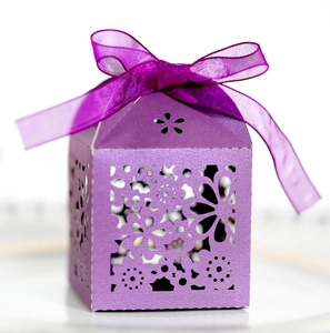 Macro detail of purple laser-cut wedding candy box with floral patterns and silk ribbon