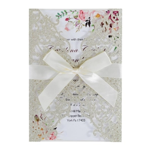 Macro detail of laser-cut glitter invitations with elegant champagne silver vine patterns