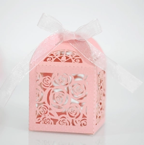 Close-up of pink laser-cut hollow rose candy gift box with elegant white ribbon bow