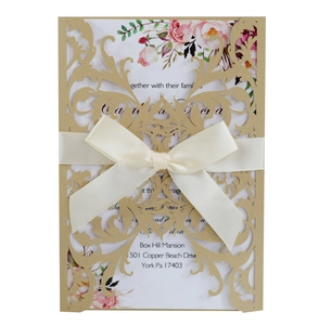 Detail of laser-cut floral wedding invitation set with cream satin bow and floral insert