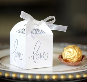 Detailed view of white hollowed Love candy box with silk ribbon on an elegant plate