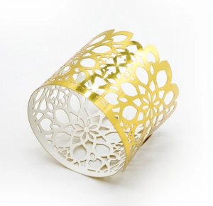 Macro detail of gold laser-cut napkin ring with intricate floral patterns and cutout design