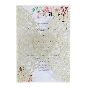 Detail showing laser-cut heart pattern on gold glitter invitation card with floral insert