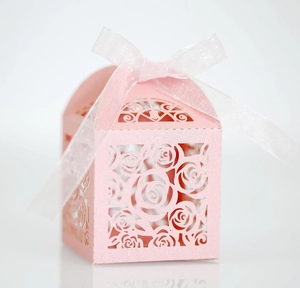Close-up of pink laser-cut favor box with hollow rose pattern and white ribbon bow