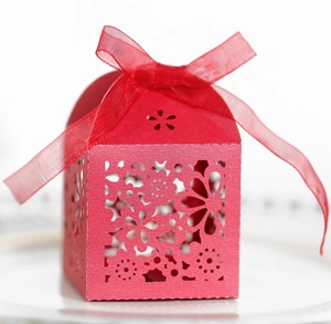 Macro shot of red laser-cut floral wedding favor box with pearl paper and silk ribbon
