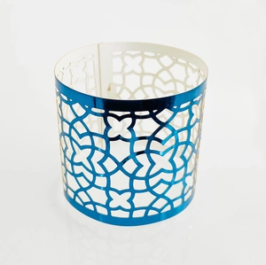 Close-up of laser-cut reflective blue napkin ring with geometric star patterns on white background
