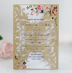 Macro detail of laser-cut gold wedding invitation with pink rose floral inner card