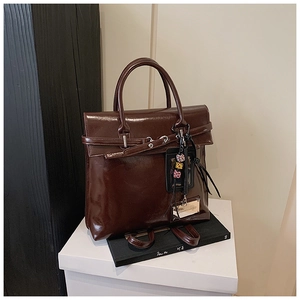 Detail of dark brown glossy leather backpack featuring vintage buckles and leopard pendant