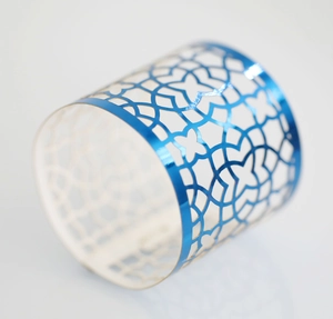 Close-up of bright blue hollow geometric napkin ring with metallic laser-cut pattern