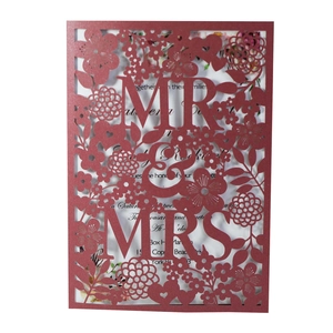 Macro shot of red laser-cut Mr & Mrs wedding invitation with intricate floral details