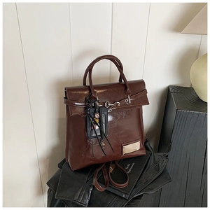 Gros plan détaillé du sac à dos en cuir marron brillant avec accents métalliques et charme