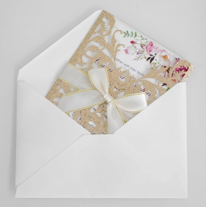 Detailed laser cut rose pattern on gold glitter wedding card with white satin bow
