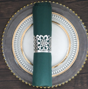 Detail of silver hollow metal napkin ring with green fabric on elegant dinnerware