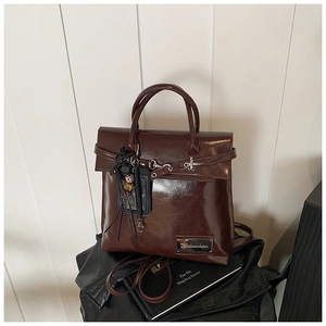 Vue détaillée du sac marron foncé brillant avec boucles vintage et pendentif à perles