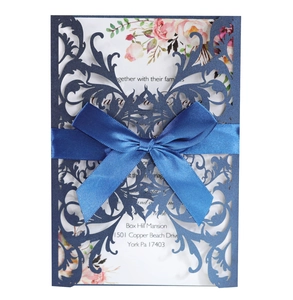 Detail of laser-cut navy blue wedding invitation with satin bow and floral insert