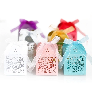 Detail of laser-cut floral candy gift boxes with elegant ribbon bows in multiple colors