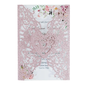 Detailed laser-cut pink glitter wedding invitation with intricate heart scrollwork and floral card