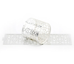 Macro view of silver hollowed-out napkin rings with geometric laser-cut petal patterns