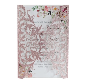 Close-up of laser-cut rose gold glitter wedding invitation with floral insert