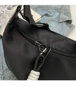 Close-up of smooth metal zipper with woven rope puller on black canvas crossbody bag