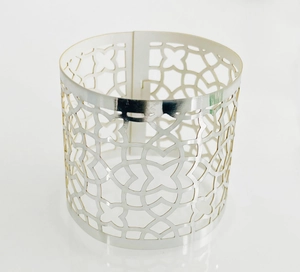 Macro detail of silver hollow napkin ring with geometric floral cutout patterns