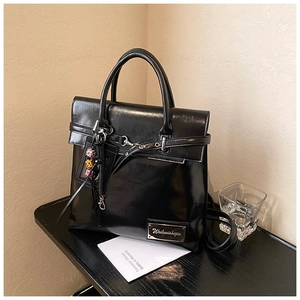 Détail du sac à dos en cuir noir brillant avec poignée et breloque en perles sur le côté