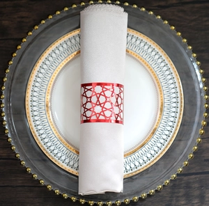Macro shot of a red geometric hollowed metal napkin ring on a white cloth napkin