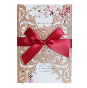 Laser cut rose gold glitter wedding invitation with burgundy satin bow and floral insert