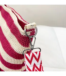Detail eines stabilen Metallhakens an der rosa-beigen gewebten Tasche mit Chevron-Gurt