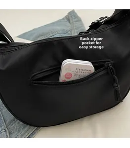 Detail view of the back zipper pocket on a black nylon crescent crossbody bag