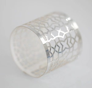 Close-up of a silver hollow napkin ring with modern geometric floral cutout patterns