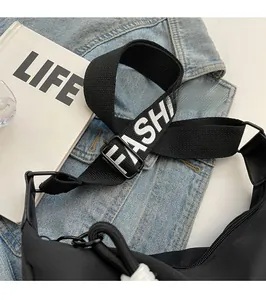 Detail view of black canvas crossbody bag with adjustable wide fashion letter strap