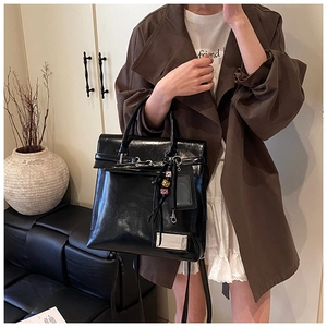 Detail of glossy black patent leather backpack with tassel and decorative charms