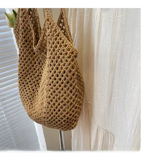 Detail of hand-woven hollow straw tote bag in khaki with a diamond mesh pattern