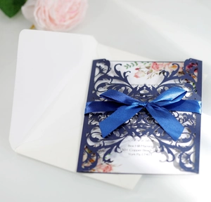 Detail of laser-cut navy wedding invitation with silk bow and floral insert card