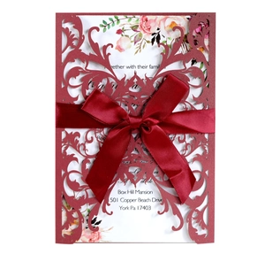Macro shot of laser-cut swirl pattern on dark red cardstock with a satin ribbon bow