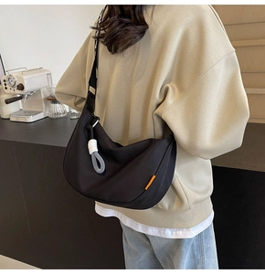 Detail of black crescent canvas crossbody bag with wide patterned strap on model