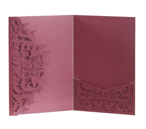 Close-up of laser-cut rose patterns on pearlescent burgundy wedding invitation cover