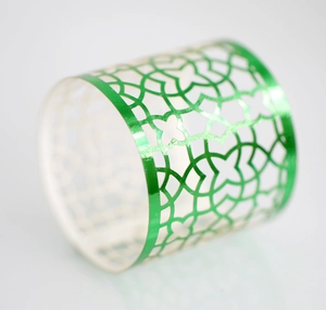 Detail showing the intricate hollow geometric pattern on a green metallic napkin ring