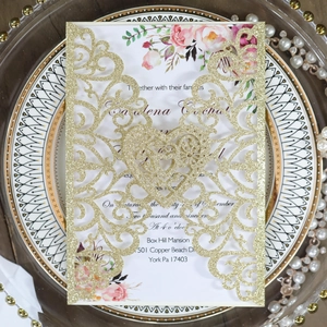 Detail of laser-cut glitter gold wedding invitation with floral inner card on a decorative plate