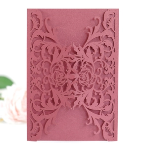 Detail of laser-cut rose patterns on elegant burgundy wedding invitation card