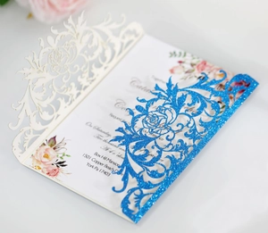 Detail of laser-cut wedding invitation with blue glitter band and floral inner card