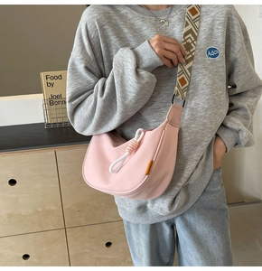 Pink canvas half-moon crossbody bag with decorative knot and ethnic patterned strap