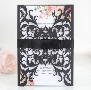 Detail of laser cut black wedding invitation with elegant ribbon and floral insert card