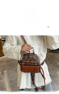 Detail of vintage plaid mini backpack with brown leather trim and metal zipper