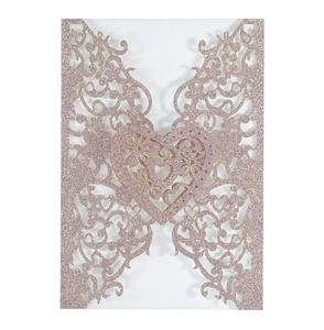 Macro detail of laser-cut rose gold glitter wedding invitation with heart floral patterns