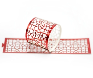 Macro view of red laser-cut napkin rings with intricate geometric floral hollow patterns